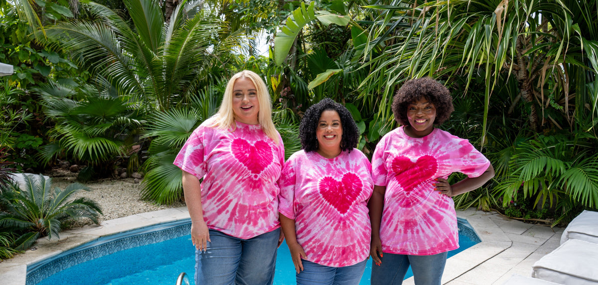 Three women laughing by the pool in the hand-dyed Pink Heart tee