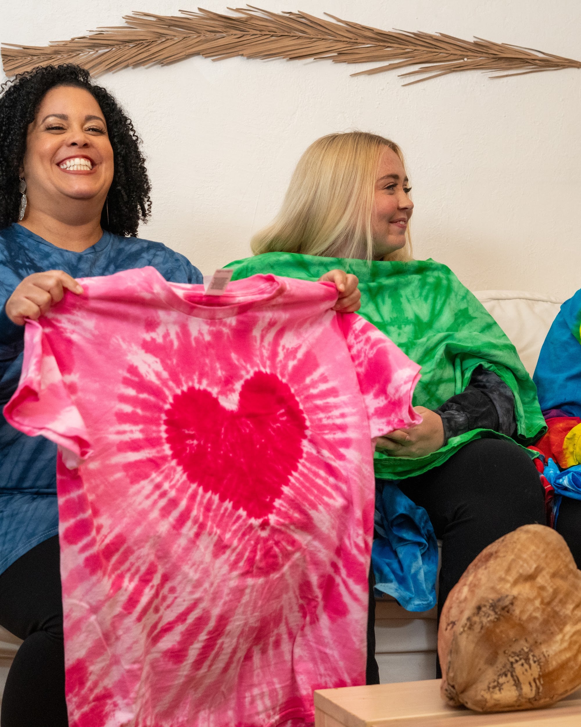 A model holding up a folded hand-dyed tie-dye shirt