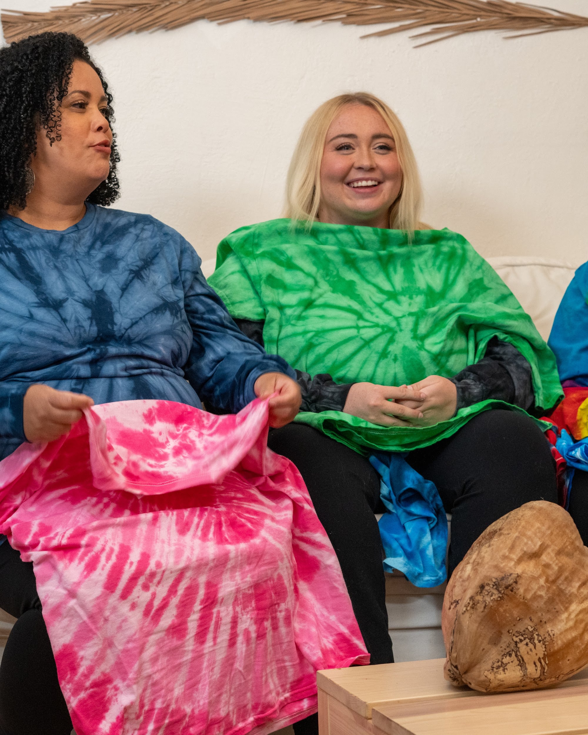 A model holding up a folded hand-dyed tie-dye tee