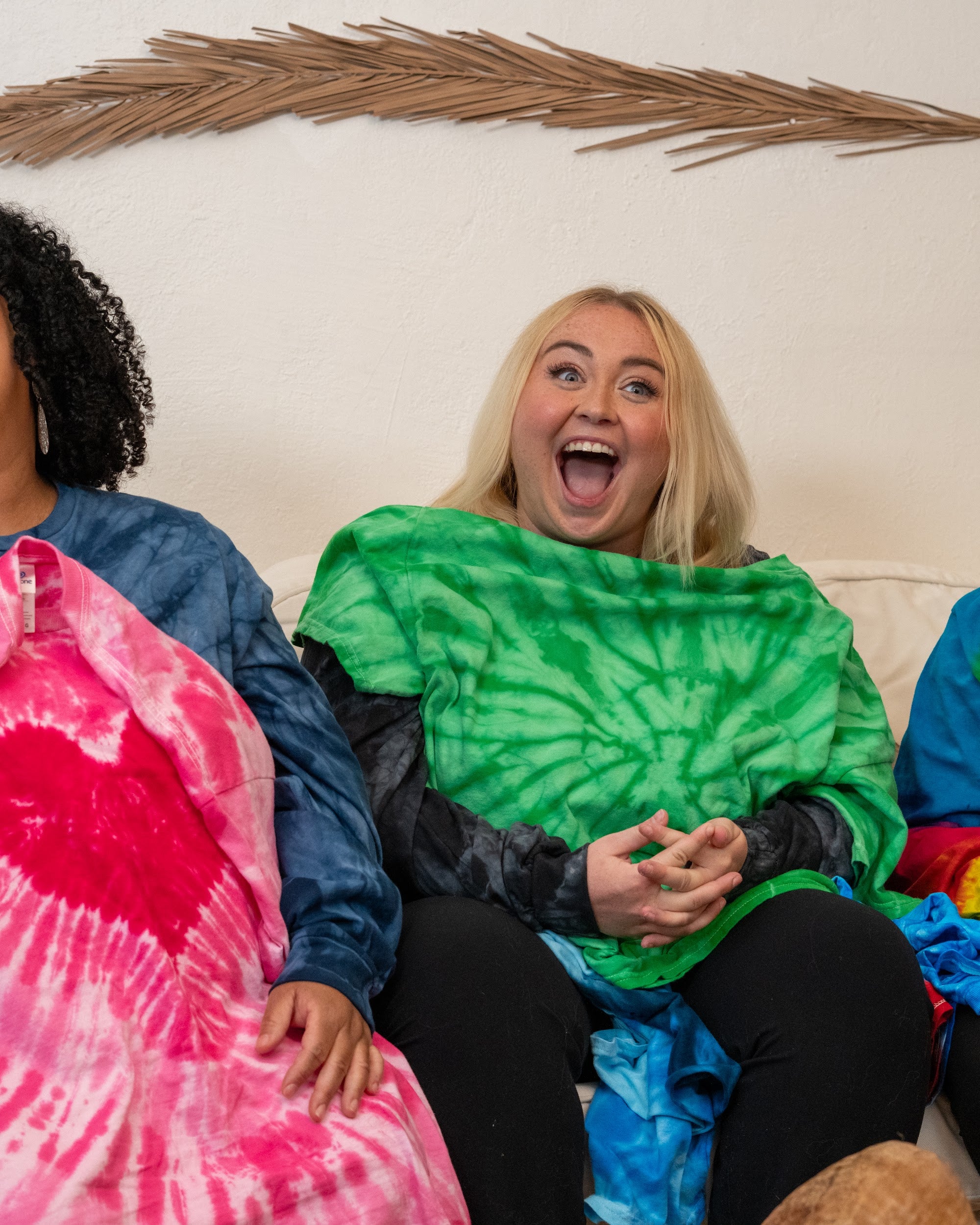 Three women holding folded hand-dyed mystery tie-dye tees